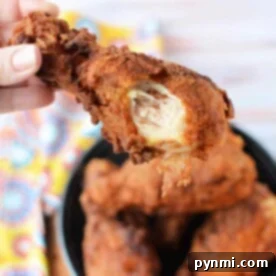 Fried Chicken's Perfect Fry: Optimal Oil Temperature 8 A hand grips a crispy fried chicken drumstick with a bite missing, hovering tantalizingly above a bowl brimming with more golden pieces. Ever wonder how hot should oil be for fried chicken? The perfect temperature ensures that irresistible crunch.