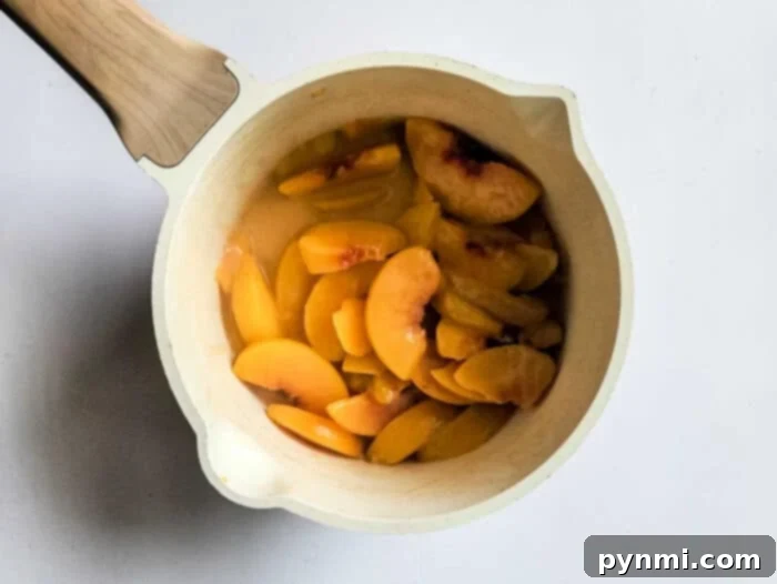 Sunshine Peach Pockets 3 A single peach hand pie with a delicate fork-crimped edge, displaying a glimpse of its juicy peach filling.