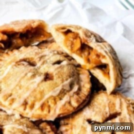 A stack of apple and peach hand pies with one cut open, revealing the luscious fruit filling inside.