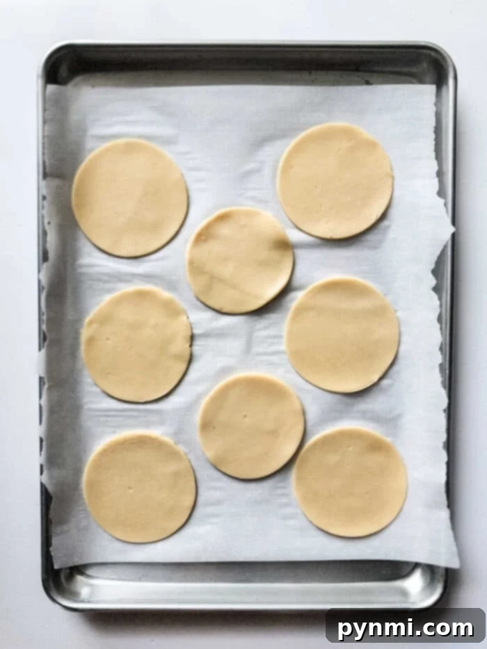 Sunshine Peach Pockets 6 Eight round dough pieces, reminiscent of the gentle sweetness found in peach hand pies, rest poised on a parchment-lined baking sheet.