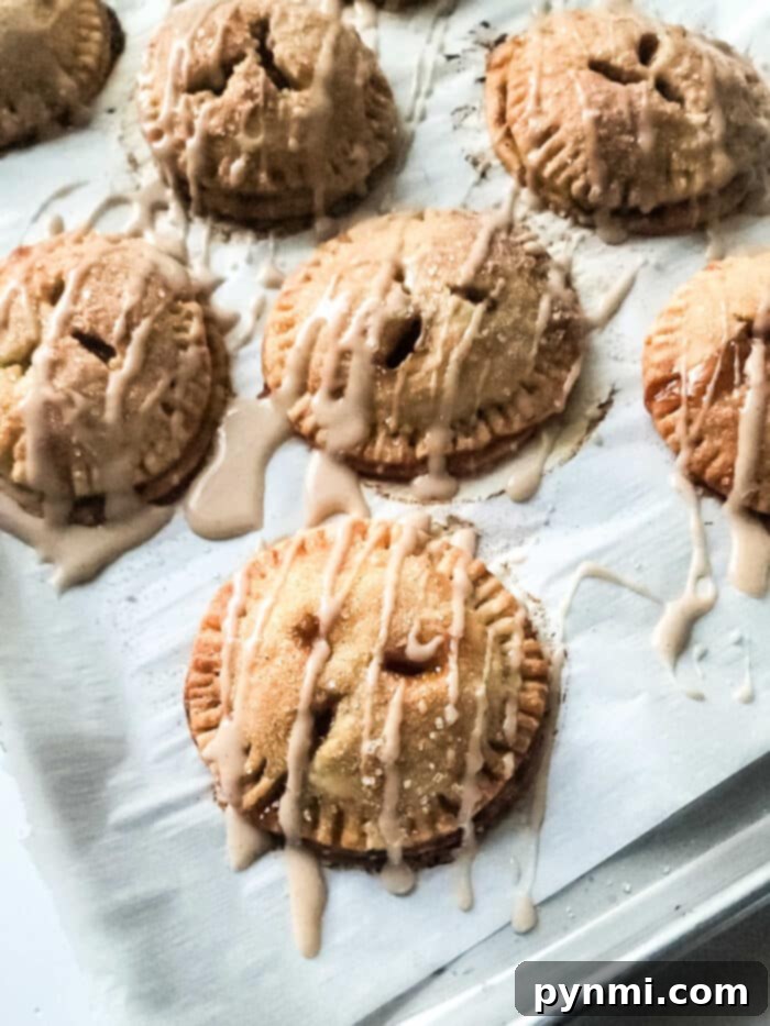 Sunshine Peach Pockets 7 Mini peach hand pies with drizzled icing rest enticingly on a baking sheet.