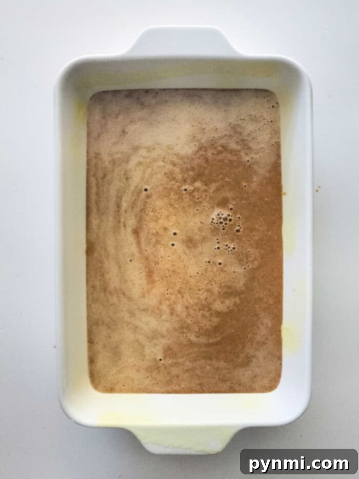 Effortless Sweet Potato Dessert 3 White rectangular baking dish with a rich caramel glaze on a Sweet Potato Dump Cake, viewed from above.