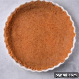 Flawless Graham Cracker Cheesecake Crust 8 Graham cracker crust for cheesecake elegantly nestled in a fluted tart pan rests on a gray surface, ready to charm with its simplicity and flavor.
