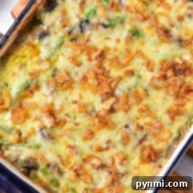 A delightful frozen green bean casserole topped with melted cheese and crispy fried onions, served in a blue rectangular dish.