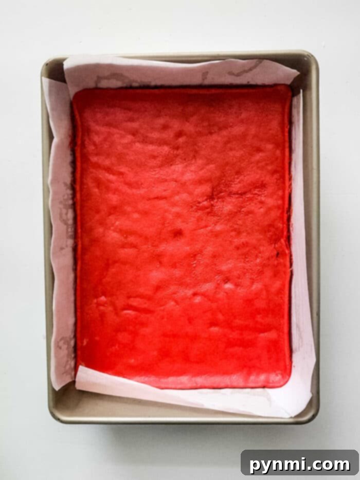 Decadent Sugar Cookie Lasagna 3 Close-up of a festive peppermint dessert lasagna slice, showing vibrant red and green layers, topped with crushed candy canes.