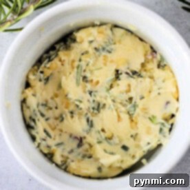 Cowboy butter recipe: Herb-infused butter in a white ramekin, garnished with fresh rosemary sprigs.