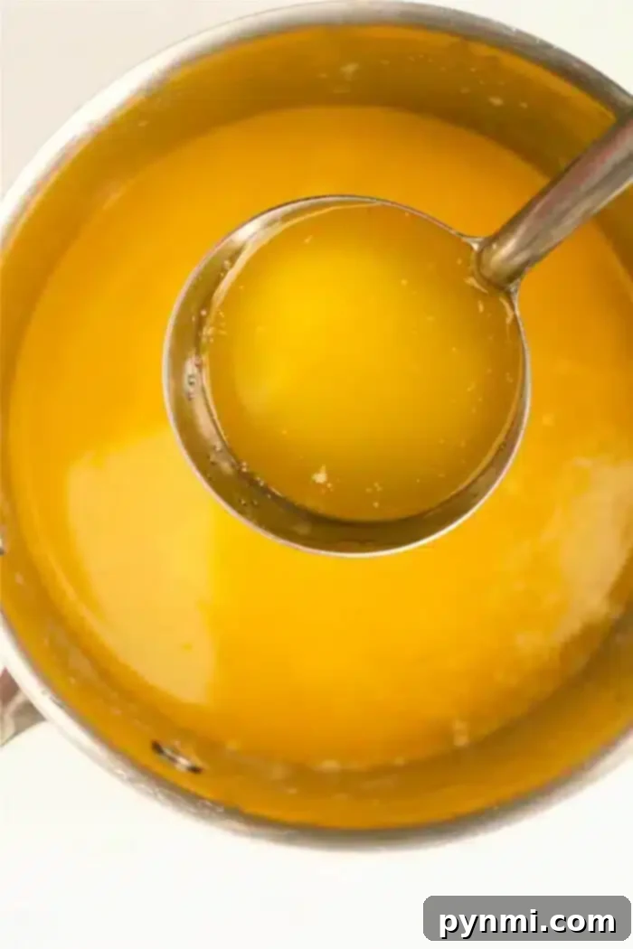 Liquid Gold: Your Guide to Perfect Melted Butter 2 A metal pot brimming with liquid butter, with a silver ladle partially lifted out, reveals the golden yellow richness inside.