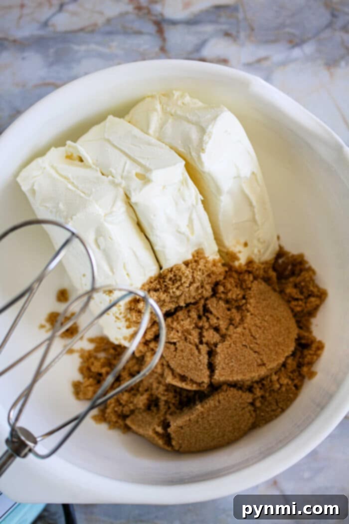 A slice of creamy Gingerbread Cheesecake on a plate, garnished with whipped cream and gingerbread cookie crumbs, set against a cozy fall backdrop.