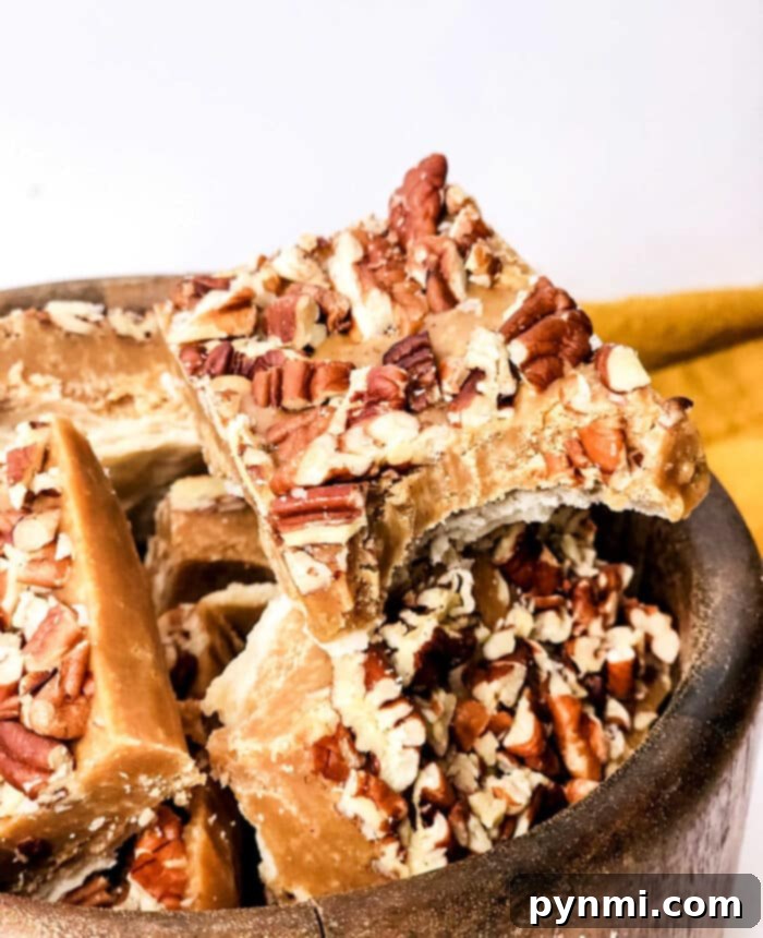 Close-up of a square piece of maple pecan fudge with pecans scattered on top