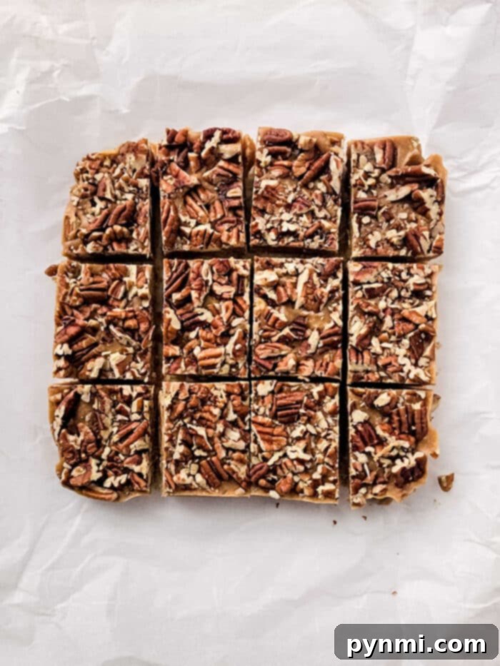 Multiple pieces of maple pecan fudge cut into squares, stacked on a white surface