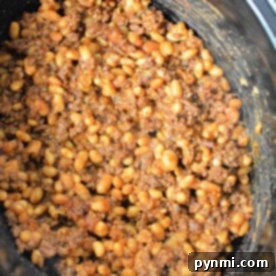 Close-up of baked beans with ground beef simmering to perfection in a slow cooker.
