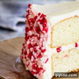 Cool Peppermint Cloud 5 A slice of white cake with peppermint frosting and red and white sprinkles sits elegantly on a plate.