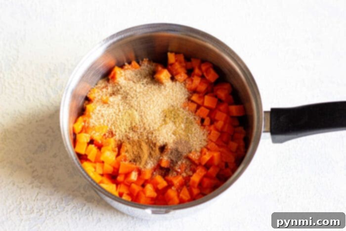 Chopped pumpkin topped with brown sugar and cinnamon meld harmoniously in a saucepan, creating a delightful blend reminiscent of pumpkin jam.
