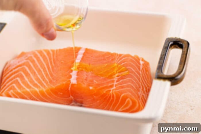 Close-up of a herb-crusted salmon fillet on a baking sheet, showcasing the vibrant green crust before baking.
