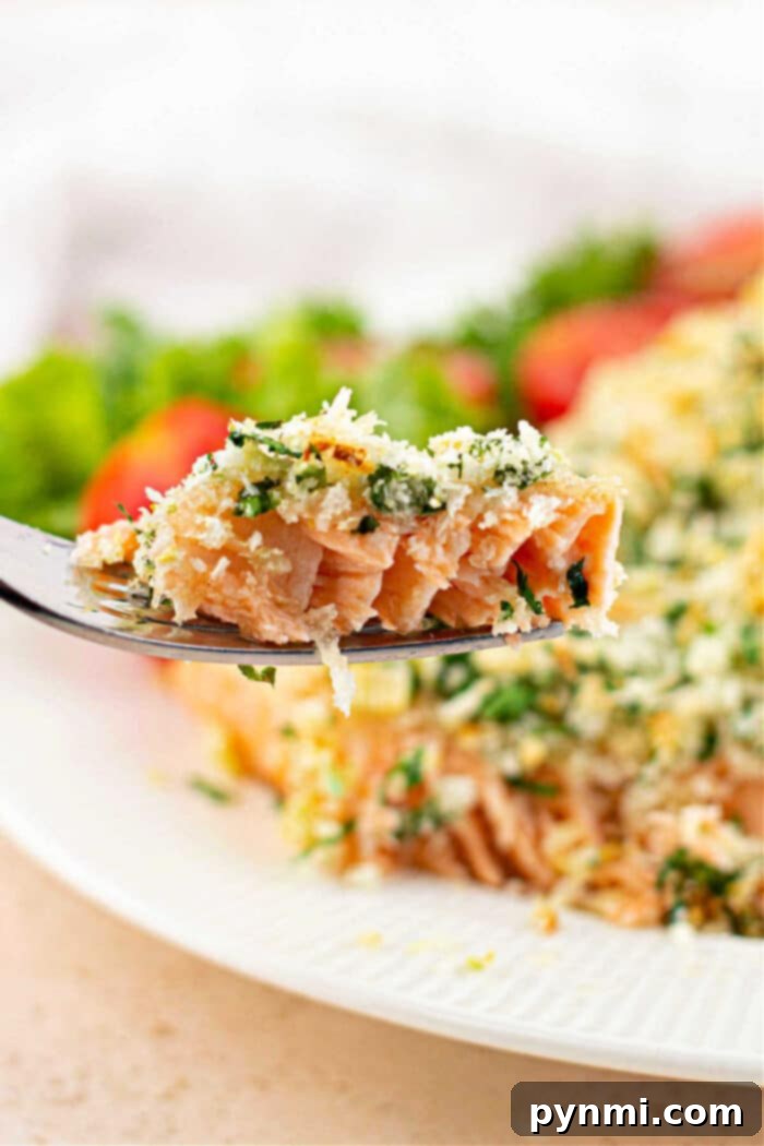 A beautifully presented whole herb-crusted salmon, flaked and ready to be served, highlighting its succulent texture.