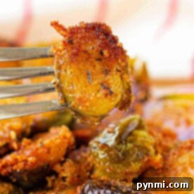 Close-up of a fork holding a crispy, Parmesan-crusted Brussels sprout slice.