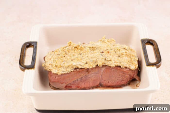 Crunchy Parmesan Steak 6 steak with a mustard and Parmesan crust in a white baking dish with handles.