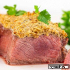Close-up of a medium-rare crusted Parmesan steak topped with a crispy crust, garnished with fresh herbs on a white plate.