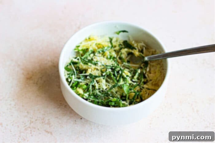 Aromatic Herb-Crusted Chicken 5 A bowl of vibrant greens, topped with slices of herbed crusted chicken, and a fork rests invitingly on the light surface.