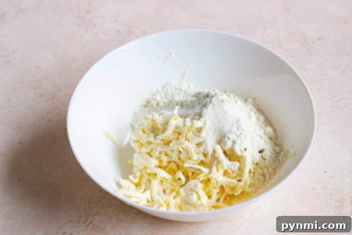 Artisan Sourdough Pie Crust 3 A white bowl brimming with shredded butter and flour rests on a light countertop, ready to craft the perfect sourdough pie crust.