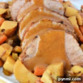 Sliced eye of round roast beef with gravy, nestled amongst an array of slow-cooked roasted potatoes, carrots, and root vegetables.