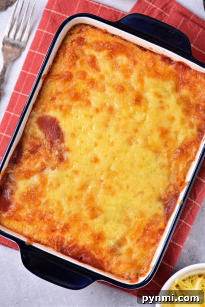 Hearty Mexican Cornbread Bake 5 A delectable cheesy mexican casserole sits in a rectangular dish on a red checkered cloth, reminiscent of a comforting Mexican cornbread casserole.