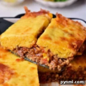 A slice of flavorful Mexican cornbread casserole with ground meat and cheese, served on a spatula.