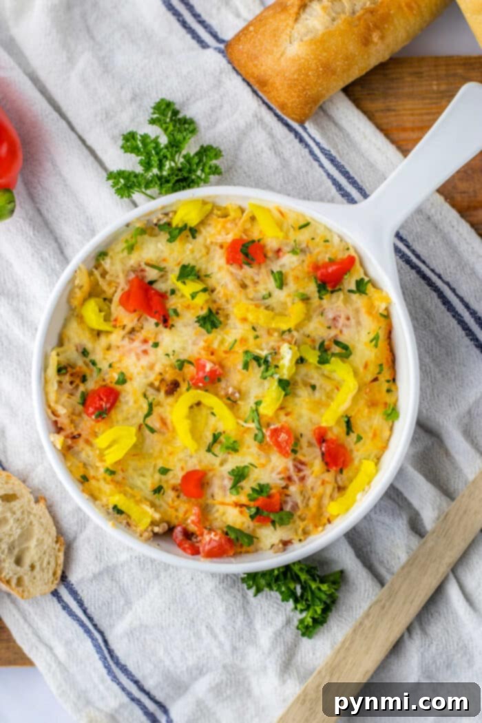 Rotel Sausage Dip, a golden-brown, bubbly hot dip in a white baking dish, ready to be served with crusty bread.