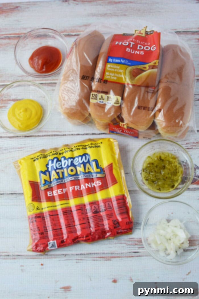Baked Hot dog ingredients: buns, beef franks, ketchup, mustard, relish, and chopped onions rest on a wooden surface, ready to create perfect hot dogs in the oven.