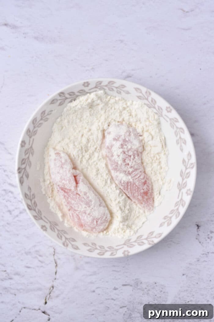 Beer-Battered Chicken Strips 5 Raw chicken tenders coated in flour, arranged in a decorative bowl.