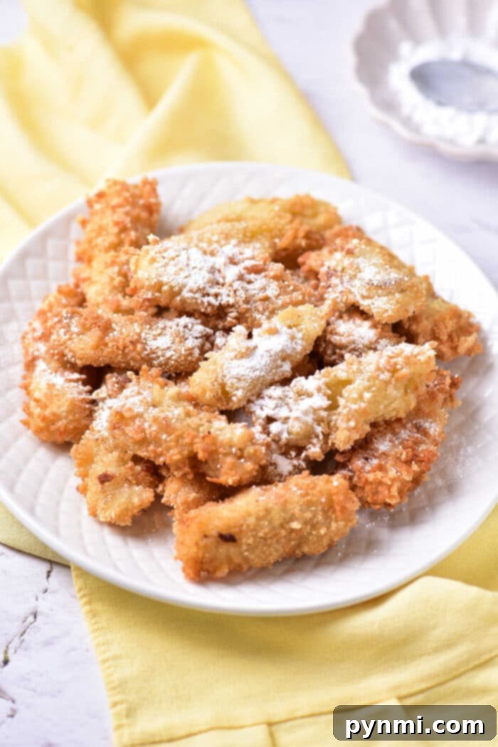 Golden Banana Tempura Perfection 2 Golden brown deep-fried banana tempura bites stacked on a white plate, ready to be served as a sweet dessert.