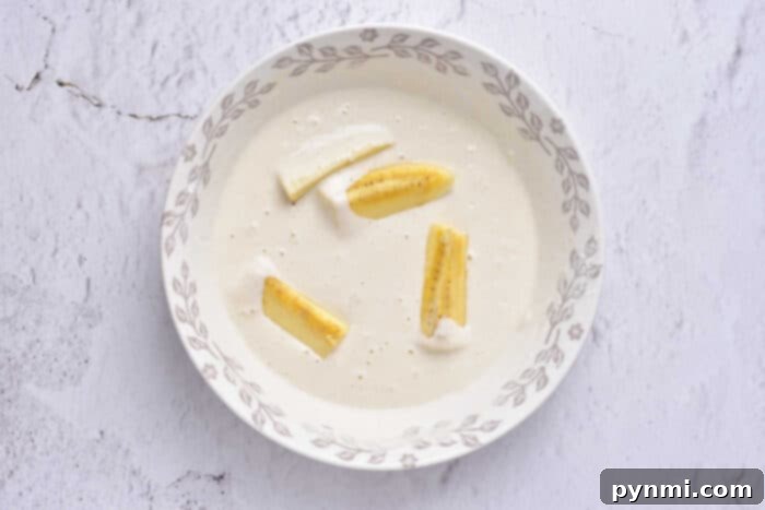 Golden Banana Tempura Perfection 4 A beautifully arranged bowl of banana tempura slices, artfully presented on a clean white background, highlighting the golden crispiness.