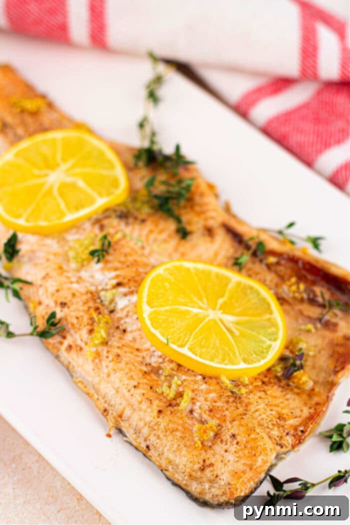 Baked Trout with Garlic and Butter, garnished with fresh herbs and lemon slices