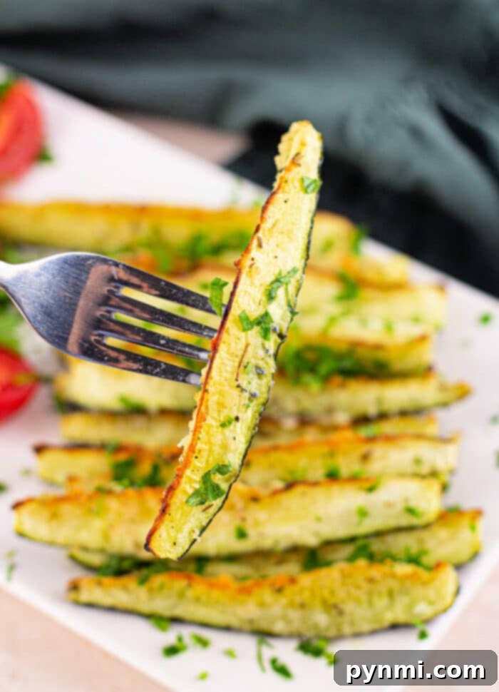 Crispy roasted zucchini spears on a baking sheet, showcasing how long to roast zucchini at 400 degrees for optimal texture.