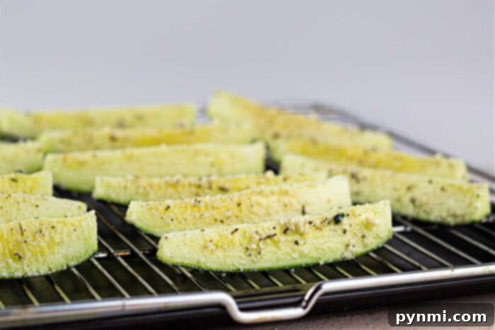 Oven-baked zucchini spears arranged on a baking sheet, perfectly seasoned and cooked.