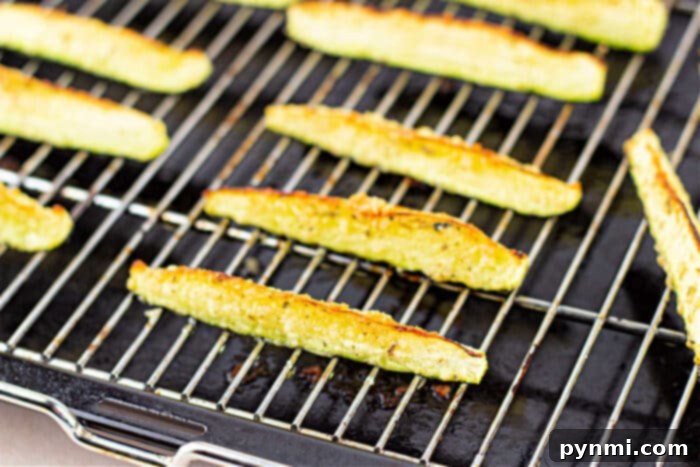 Close-up of zucchini fries on a baking sheet, lightly browned and evenly spaced, offering a hint of deliciousness for those curious about how long to roast zucchini to perfection.