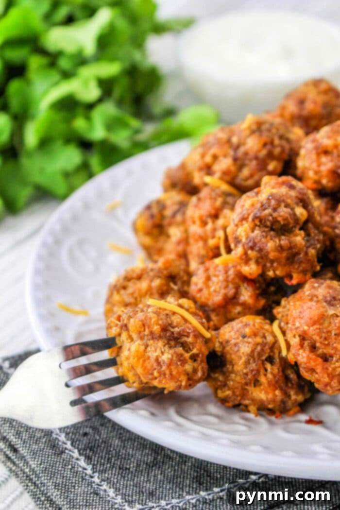 Taco Poppers 6 Deep-fried Bisquick taco balls arranged on a cooling rack with a plate of dipping sauce in the background.