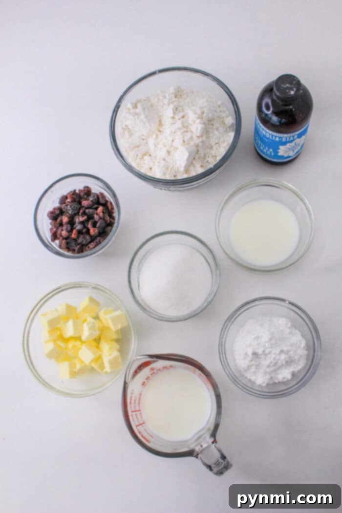 On a rustic wooden table, an array of fresh ingredients for baking Bisquick scones is beautifully arranged: a bowl of all-purpose flour, a scoop of granulated sugar, cold cubed butter, a pitcher of milk, a small dish of dried cranberries, and a bottle of vanilla extract. A classic yellow box of Bisquick stands prominently, suggesting its central role in the recipe. The scene hints at the process of creating delicious, homemade scones, possibly finished with a sprinkle of powdered sugar.