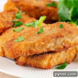 Close-up of crispy Fish Fry fillets, perfectly breaded and fried, garnished with fresh parsley on a pristine white plate.