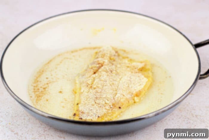 Fried Swai Fish fillet, perfectly coated in corn flour, sizzles in a butter-filled pan.