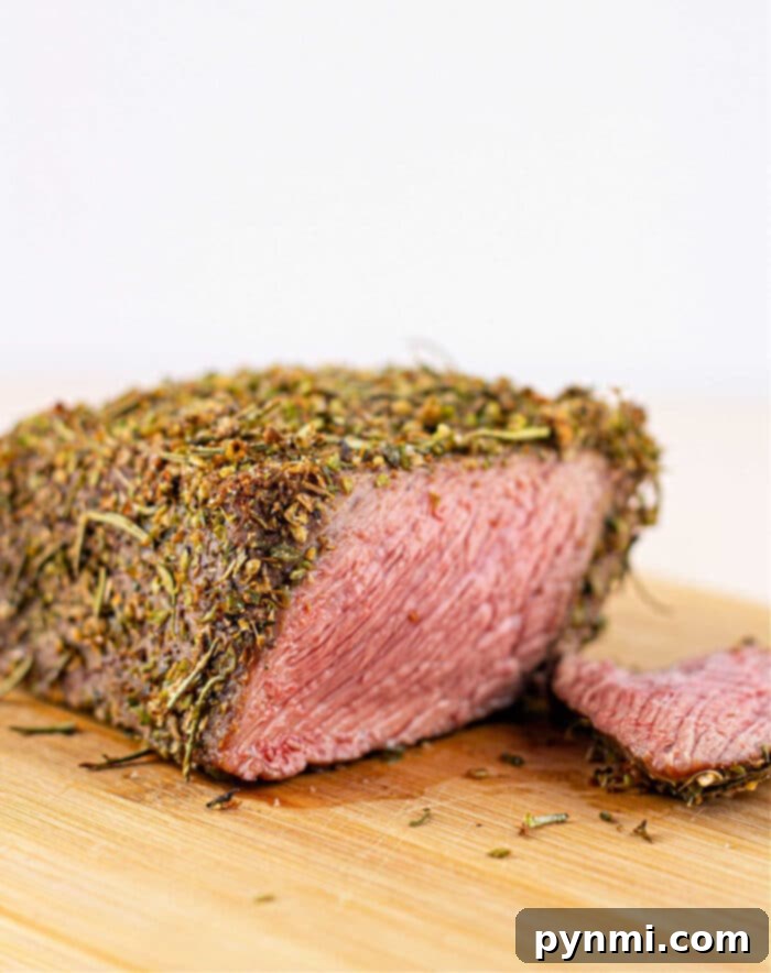 The final masterpiece: perfectly sliced bottom round roast, beautifully garnished with herbs and cherry tomatoes, ready to be enjoyed with a rich gravy.