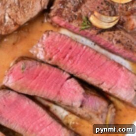 Sliced medium-rare steak with garlic and seasoning on a plate, capturing the essence of how to cook beef tenderloin medallions to perfection.