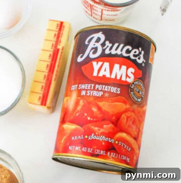 Velvet Southern Sweet Potato Dream 3 A 40-ounce can of Bruce’s Yams, labeled 'Cut Sweet Potatoes in Syrup' and 'Real Southern Style,' sits on a white surface. Nearby are a stick of butter, a measuring cup, and other baking ingredients, highlighting the ease of making sweet potato pie with canned yams.