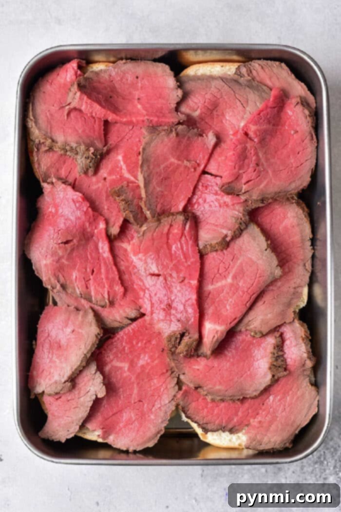 Slices of rare beef, perfect for leftover tri tip recipes, are arranged in a metal tray on a gray background.
