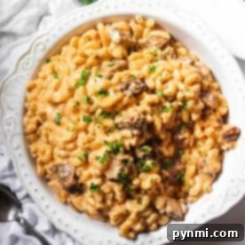 A white bowl filled with creamy macaroni and cheese topped with chopped herbs, perfect for pairing with your leftover tri-tip recipes.