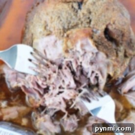Slow Roasted Boston Butt Perfection 7 Shredded Boston Butt in a baking pan with two forks pulling the tender roast pork apart.