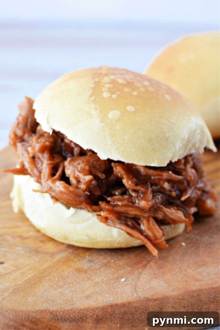 Slow Roasted Boston Butt Perfection 9 Appetizing pulled pork sliders on buns, garnished with fresh herbs and ready to serve.