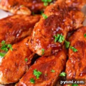 Succulent oven-baked chicken tenders glisten with a savory glaze, elegantly garnished with fresh parsley on a plate.