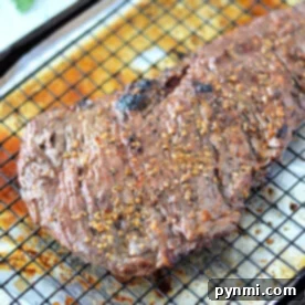 A perfectly broiled skirt steak resting on a wire rack with a savory seasoning on top basks in the warmth of the oven.