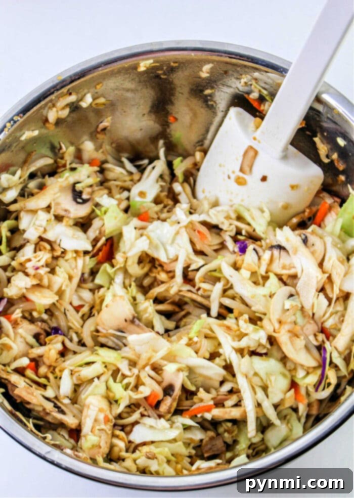 A bowl of fresh spring roll filling, featuring finely chopped cabbage, bean sprouts, and mushrooms.